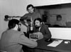 Pr&eacute;paration de l'&eacute;mission &laquo; �Le cahier ontarien� &raquo; de CJBC, avril 1970. L'annonceur Claude Miguet (� gauche) discute avec le politicien John Harney. On aper�oit, debout, le r&eacute;alisateur Jean-Pierre Morin et, en arri�re-plan, le technicien Brian Wood.